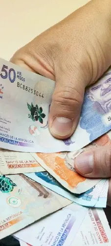 Mano sosteniendo billetes colombianos